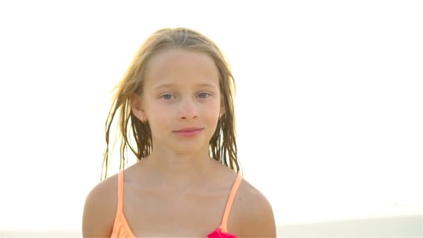 Portret van een klein meisje, kijkend naar de camera en lachende achtergrond, prachtige lucht en zee. SLOW MOTION — Stockvideo