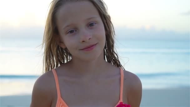 Portret van een klein meisje, kijkend naar de camera en lachende achtergrond, prachtige lucht en zee. SLOW MOTION — Stockvideo