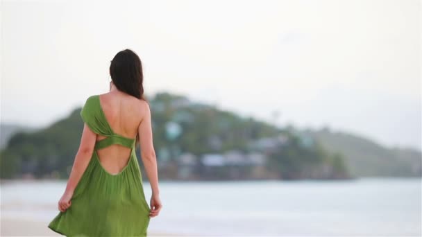 Молода красива жінка на тропічному узбережжі. Туристична дівчина в зеленій мрії на пляжі — стокове відео