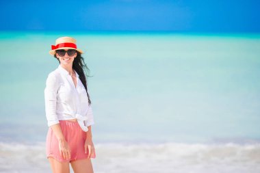 Genç ve güzel bir kadın tropik deniz kıyısında eğleniyor. Mutlu kız arka planda mavi gökyüzü ve Karayip adasında denizde turkuaz su