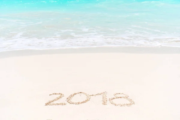 2018 escrito à mão na praia de areia com onda de oceano macio no fundo — Fotografia de Stock