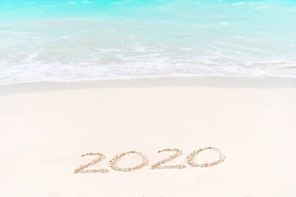 2020 escrito à mão na praia de areia com onda de oceano macio no fundo — Fotografia de Stock