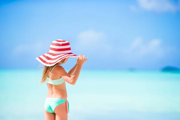 Schattig meisje in grote rode hoed op het strand — Stockfoto