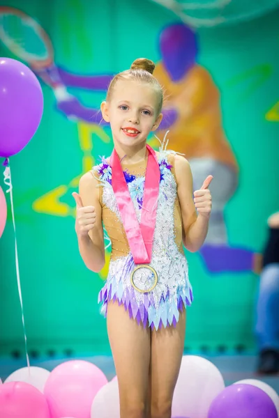 Little charming gymnast with medal after the rhythmic gymnastics competition