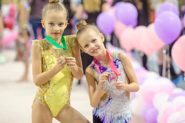 Little charming gymnasts with medals after the rhythmic gymnastics competition