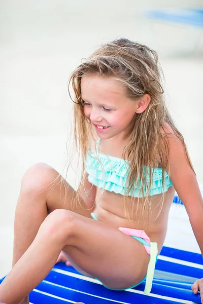Malá holčička baví na tropické pláži hraje na lehátko — Stock fotografie
