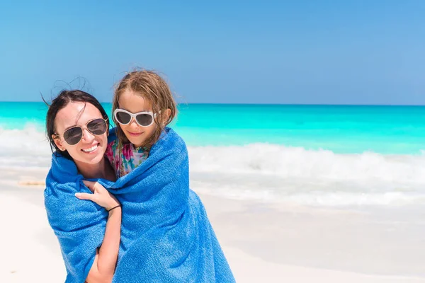 Mamãe envolve uma filha pequena com uma toalha depois de nadar no mar. Mãe e filhinha aproveitando o tempo na praia tropical — Fotografia de Stock
