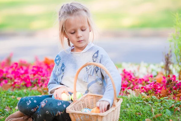 Portrait of little girl with a basket full of Easter eggs on spring day outdoors — Stock Photo, Image