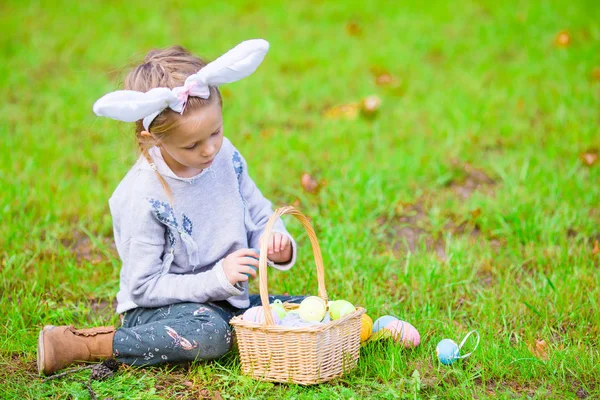 Retrato de criança usando orelhas de coelho com uma cesta cheia de ovos de Páscoa no dia da primavera ao ar livre — Fotografia de Stock