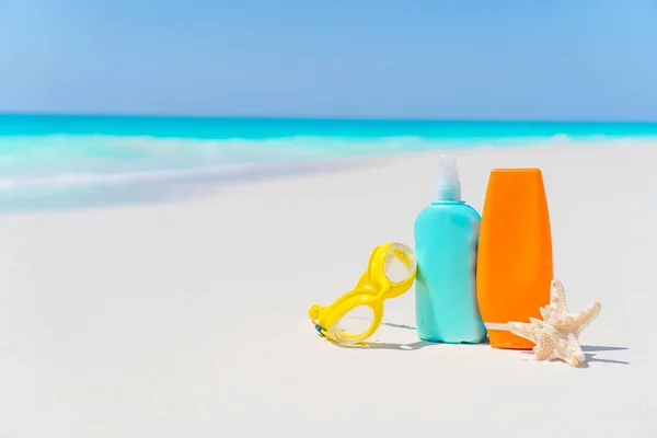 Botellas de crema solar, vasos, estrellas de mar en la playa de arena blanca — Foto de Stock