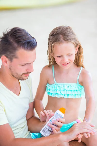 Giovane padre che applica la crema solare alla figlia sulla spiaggia. Protezione solare — Foto Stock