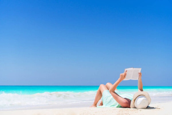 Young woman reading book during tropical white beach