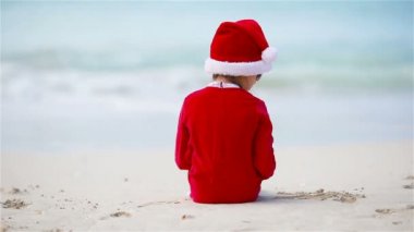 Noel tatilinde beyaz plajda Noel şapkalı güzel bir kız.