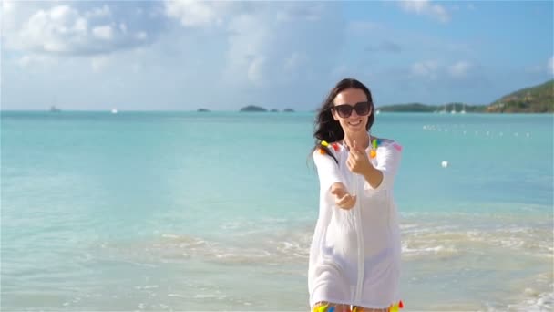 Молода красива жінка розважається на тропічному узбережжі. Щаслива дівчина біжить на білому піщаному тропічному пляжі — стокове відео