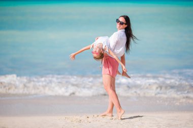 Tropik plajda küçük sevimli bir kız ve genç bir anne.