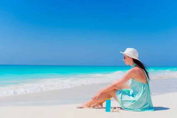 Beautiful young woman with suncream lying on tropical beach — Stock Photo, Image