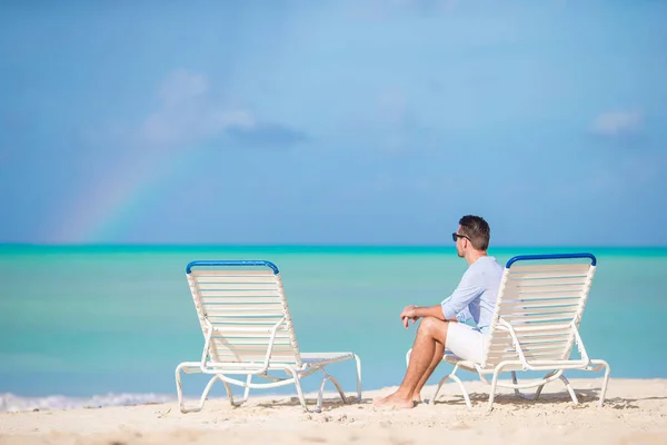 Jonge man op het strand stilhoudt boven de zonnebank alleen buiten — Stockfoto