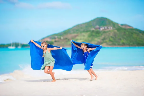 Милые девочки весело бегают с полотенцем и наслаждаются отдыхом на тропическом пляже с белым песком и бирюзовой водой океана — стоковое фото