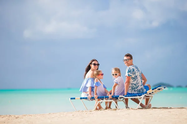 Feliz hermosa familia en la playa. Vista trasera de los padres y los niños en el chaise-lounge —  Fotos de Stock