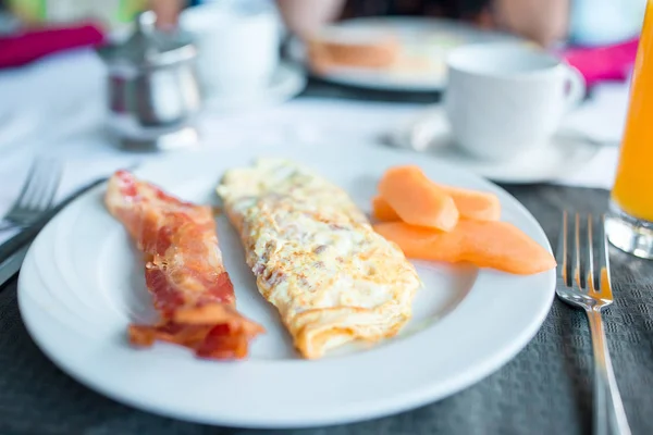 Gesundes, leckeres amerikanisches Frühstück mit Omelette und Speck auf dem Tisch im Café — Stockfoto