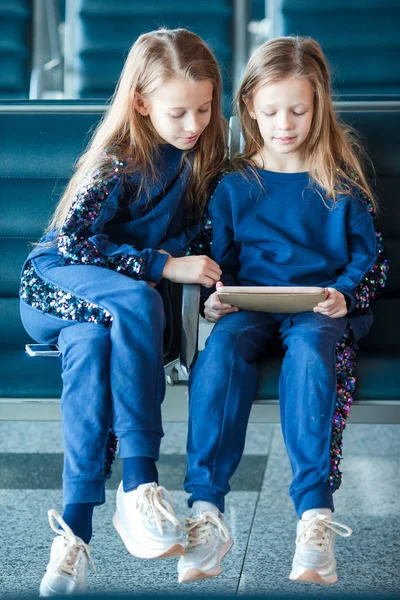 Niñas adorables en el aeropuerto esperando para el embarque jugando con el ordenador portátil — Foto de Stock