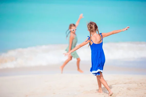 Δύο χαρούμενα κοριτσάκια διασκεδάζουν πολύ στην τροπική παραλία παίζοντας μαζί. — Φωτογραφία Αρχείου