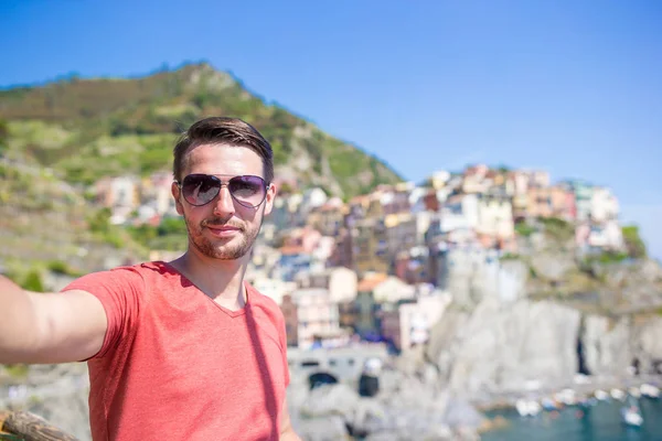 Joven turista en gafas de sol tomando selfie con vista panorámica de Manarola, Cinque Terre, Liguria, Italia —  Fotos de Stock