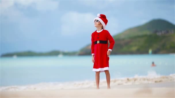 Очаровательная девушка в рождественской шляпе на белом пляже во время рождественских каникул — стоковое видео
