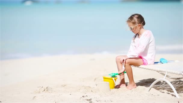 愛らしい少女が海辺での休暇におもちゃで遊んで。砂の子供遊び — ストック動画