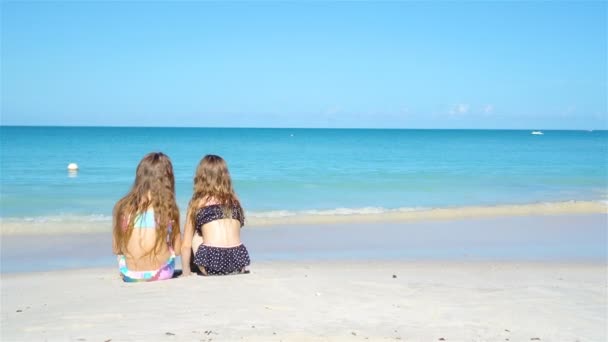 Underbara små flickor som leker med sand på stranden. Barn som sitter på grunt vatten och gör sandslott — Stockvideo