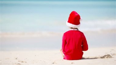 Noel tatilinde beyaz plajda Noel şapkalı güzel bir kız.