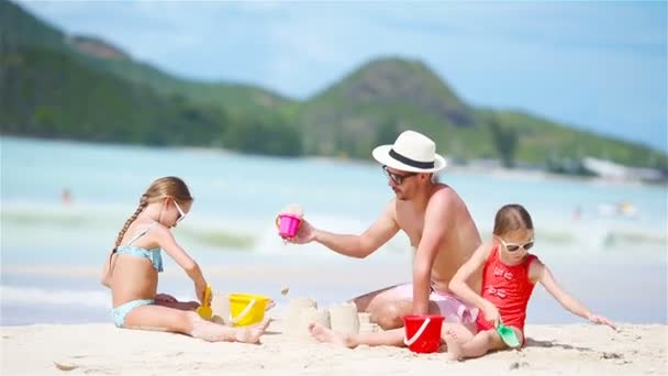 Familjen att göra sandslott på tropical vit beach. Far och två tjejer leker med sand på tropical beach — Stockvideo