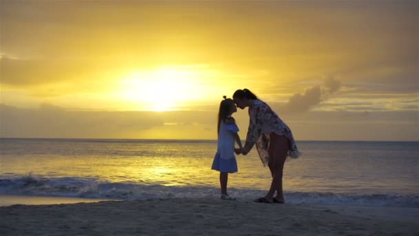 Liten flicka och lycklig mamma siluett i solnedgången på stranden — Stockvideo