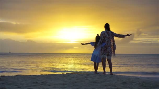 Mała dziewczynka i sylwetka szczęśliwy matki w zachód słońca na plaży — Wideo stockowe