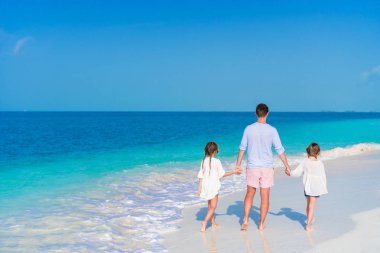 Baba ve küçük kız beyaz kumlu plaj üzerinde yürümek