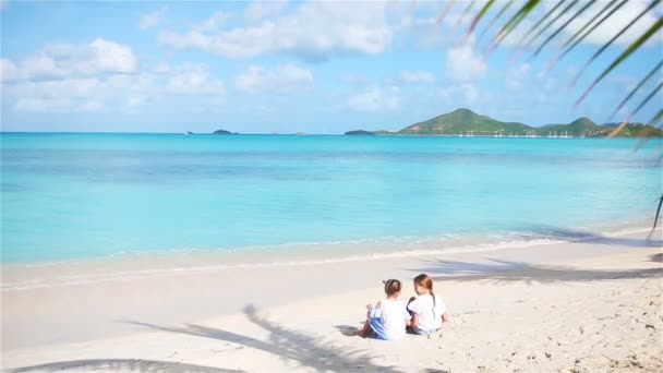 Kumsalda kumla oynayan sevimli küçük kızlar. Çocuklar sahilde oturuyor ve kumdan kale yapıyorlar. — Stok video