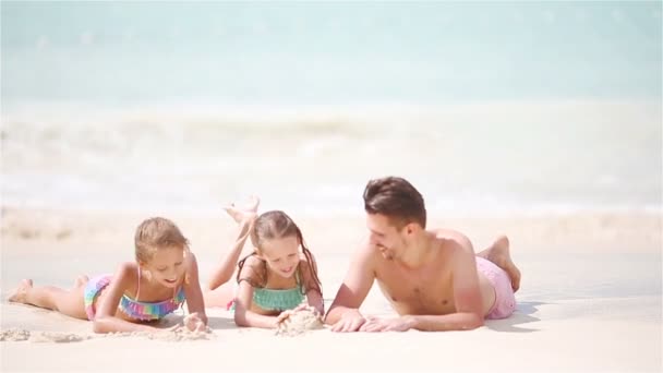 Отец и дети лежат на белом пляже — стоковое видео
