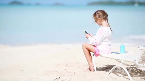 Little girl making video or photo with by her camera sitting on the sunbed — Stock Video