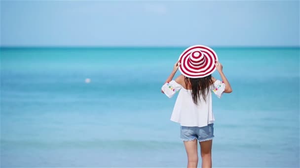 熱帯の海岸で楽しんでいる若い美しい女性。カリブ海の島で青い空とターコイズブルーの海を背景に幸せな女の子 — ストック動画