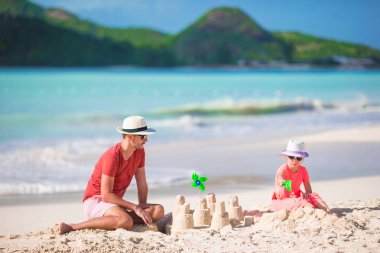 Baba ve küçük çocuk tropikal sahilinde Kumdan kale yapma