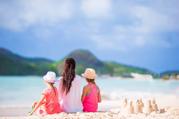 Family of mom and kids with sand castle at tropical beach — Stock Photo, Image