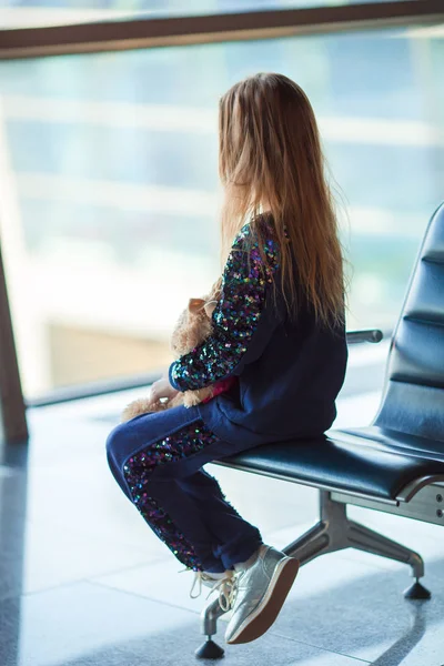 Havaalanında büyük pencerenin yanında küçük bir kız binişi bekliyor. — Stok fotoğraf