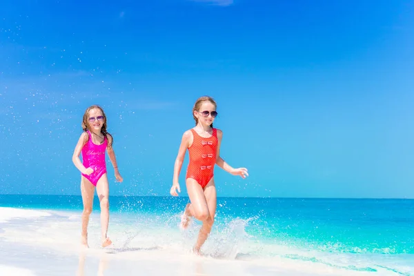 Små flickor att ha kul på tropisk strand spelar tillsammans på grunt vatten — Stockfoto