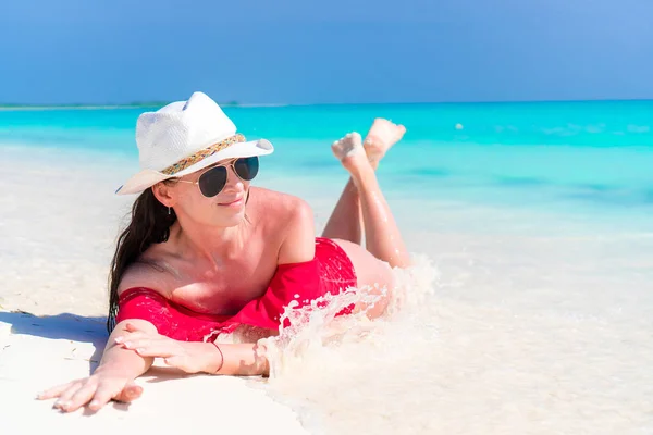 Young beautiful girl lying on snow white tropical beach in shallow water — Stock Photo, Image