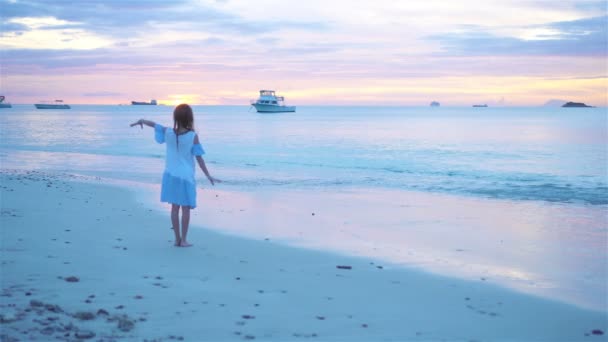 Imádnivaló, boldog kislány a fehér parton naplementekor.. — Stock videók