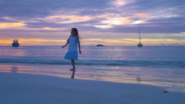 Schattig gelukkig klein meisje op wit strand bij zonsondergang. — Stockvideo