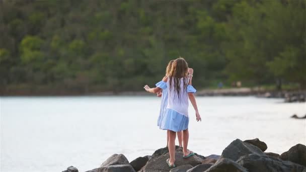 Entzückend glückliches kleines Mädchen am weißen Strand bei Sonnenuntergang. — Stockvideo