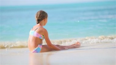 Beyaz kar kum üzerine oturan sevimli küçük kız