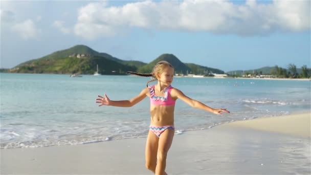 Petite fille active faisant des roues de chariot sur la plage blanche . — Video