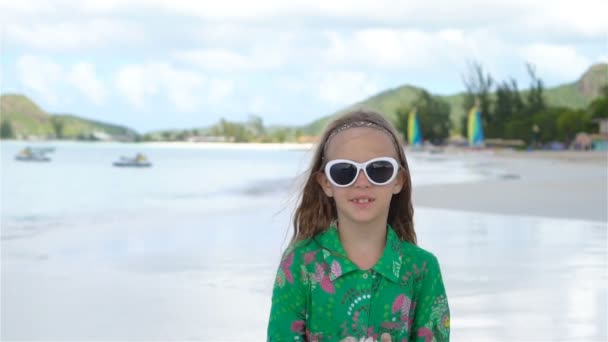 Schattig meisje met zeeschelp in handen op tropisch strand. — Stockvideo